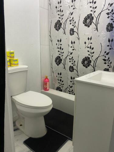 a bathroom with a toilet and a shower curtain at White Room Sparks in Spanish Town
