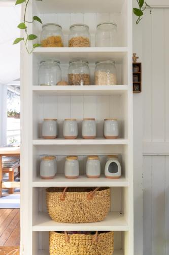 a white pantry with glass jars and baskets at SEASIDE HAVEN Luxe Four BR Oasis with Plunge Pool in Brisbane