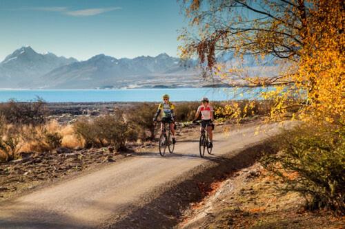 two people riding bikes down a dirt road at Lake Views at Antler Lodge in Lake Tekapo