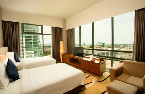 a hotel room with two beds and a desk and a chair at Zenith Hotel Kuantan in Kuantan