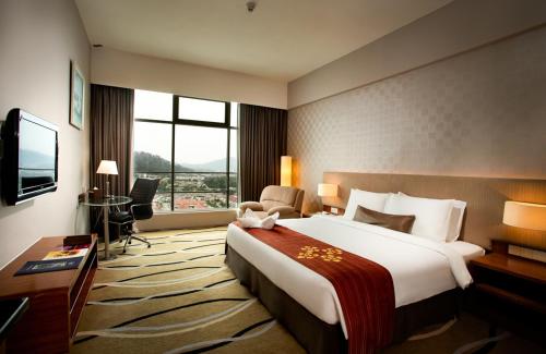 a hotel room with a large bed and a television at Zenith Hotel Kuantan in Kuantan
