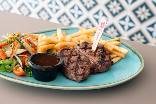 a plate of food with a steak and french fries at Palace Hotel Proserpine in Proserpine