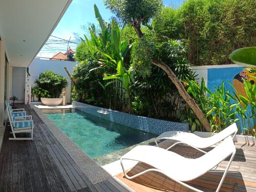 a swimming pool with two chairs in a yard at Beautiful Bali Villas in Legian