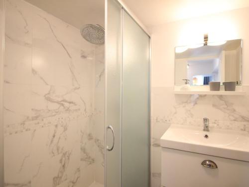 une salle de bain blanche avec une douche et un lavabo dans l'établissement T3 Jardin Wifi La Bourboule, 5 pers - FR-1-608-283, à La Bourboule