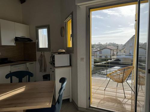 une cuisine avec une table et une vue sur un balcon dans l'établissement Duplex rénové face à la plage avec balcon et parking - FR-1-738-41, à Saint-Palais-sur-Mer