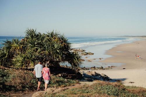 a man and a woman walking along a beach at Tweed Holiday Parks Pottsville North in Pottsville