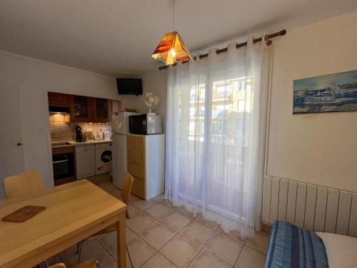 une cuisine et une salle à manger avec une table et une fenêtre dans l'établissement Argelès-Plage: T2 confortable, proche mer et commerces - FR-1-753-28, à Argelès-sur-Mer