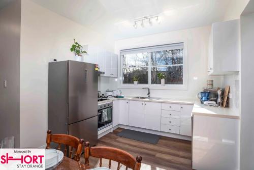 a kitchen with white cabinets and a stainless steel refrigerator at Paddington Villa 1 - Free Wi-fi, Netflix in Orange