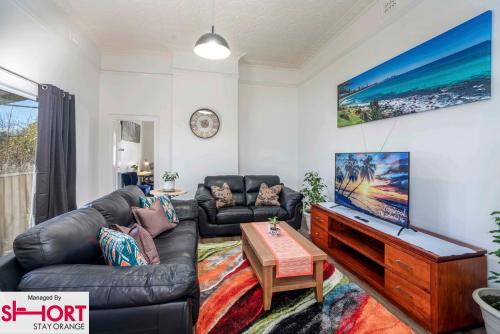 a living room with a leather couch and a table at Paddington Villa 1 - Free Wi-fi, Netflix in Orange