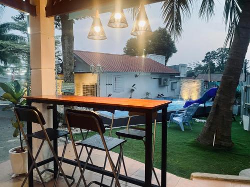 a table and chairs on a patio with a house at Jas Telaga Inn Homestay in Teluk Mas