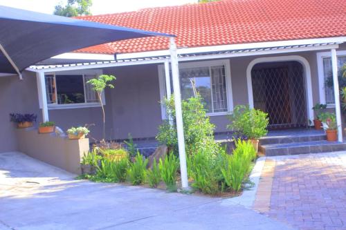 a house with a porch with plants and an umbrella at Platinum inn pty ltd in Rustenburg