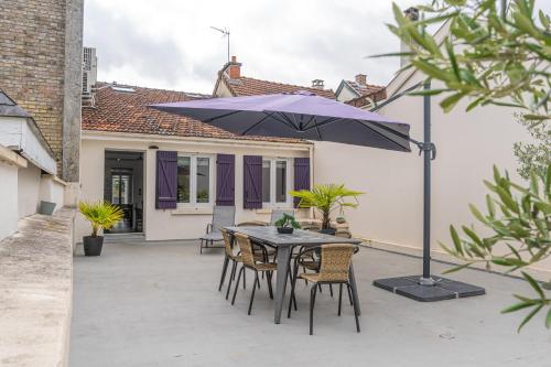 a patio with a table and chairs and an umbrella at Terrasse 86 - Terrasse & Climatisation - 4-6 personnes - BnB Epernay in Épernay
