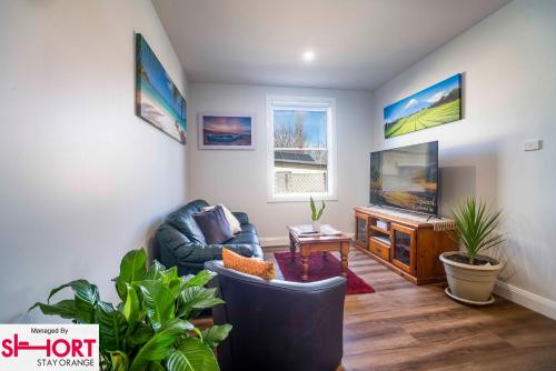 a living room with a couch and a tv at Paddington Villa 2 - wi-fi, Netflix in Orange