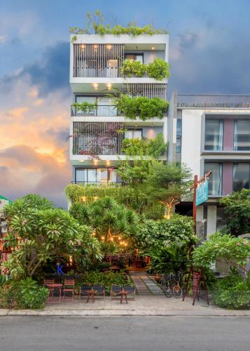 a tall building with tables and chairs in front of it at K House Apartment Danang Beach in Da Nang