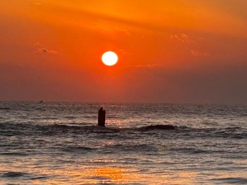 a lighthouse in the ocean with a sunset at Ubay Guest House in Trincomalee