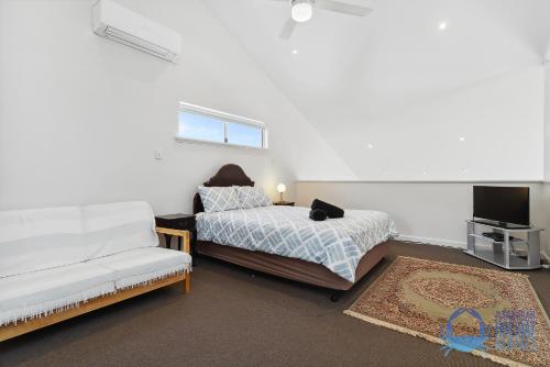 a bedroom with a bed and a couch and a tv at Relax at Falcon By The Bay in Mandurah