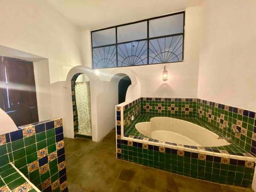 a bathroom with a large tub with green tiles at Casa Historica Colonial in Álamos