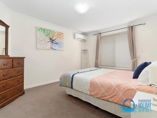a bedroom with a bed and a dresser and a window at Canal Elegance In Yunderup in Mandurah