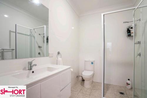 a white bathroom with a sink and a toilet at Paddington Villa 3 Close to town, Free Wi-fi, Netflix in Orange
