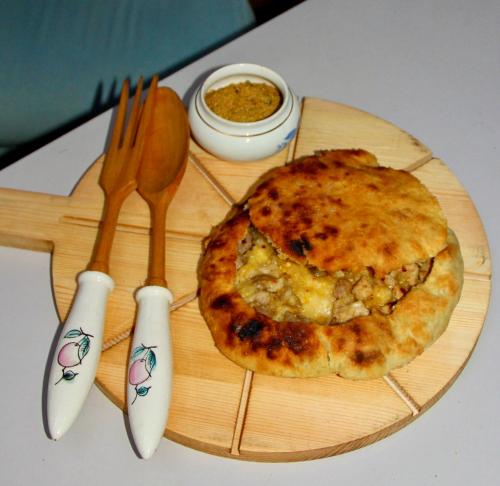 a wooden cutting board with a pizza and fork and knife at Napoli Nataxtari hotel,pool,bar,kamping in Natakhtari