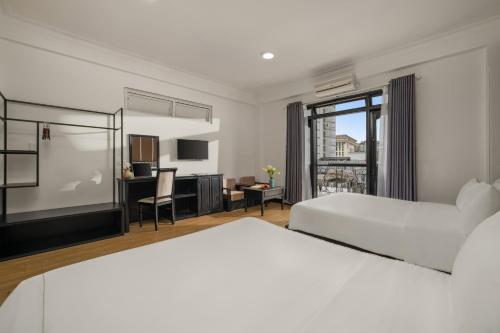 a hotel room with two beds and a desk at KLY Boutique Hotel Hue in Hue