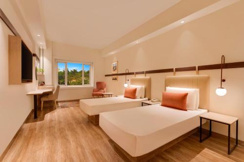 a large room with two beds and a desk at Red Fox by Lemon Tree Hotels, Hyderabad in Hyderabad