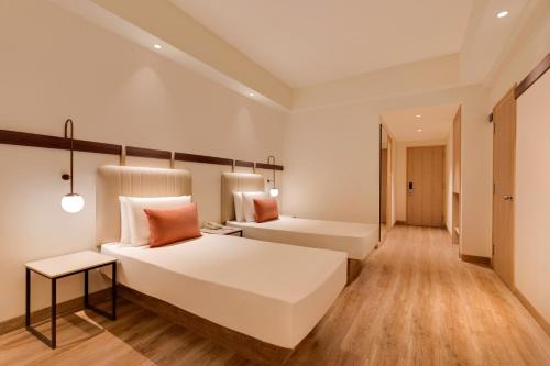 a bedroom with a large white bed and a table at Red Fox by Lemon Tree Hotels, Hyderabad in Hyderabad