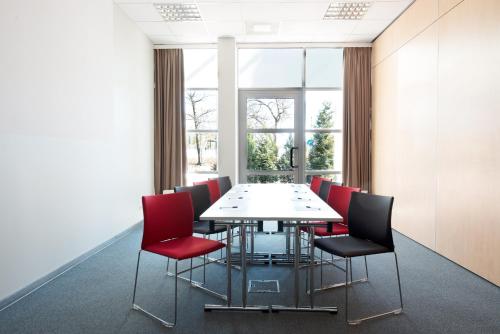 a conference room with a table and red chairs at Ibis Poznan Stare Miasto in Poznań