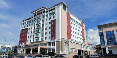 a tall building with cars parked in a parking lot at NU Hotel in Bintulu