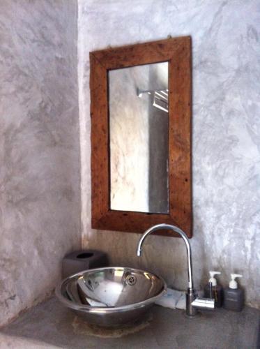 a bathroom sink with a mirror on the wall at Bangsrai Cottage in Suratthani