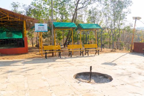 a park with two benches and a fire pit at Wild Camp- The Nature Resort in Khodāla