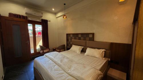 a bedroom with a large bed with white sheets at Yes Hotel By The Ganges in Rishīkesh