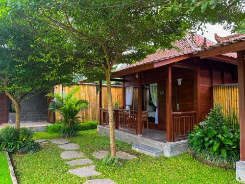 a small wooden house with a tree in the yard at Adil Villa & Resort in Ubud