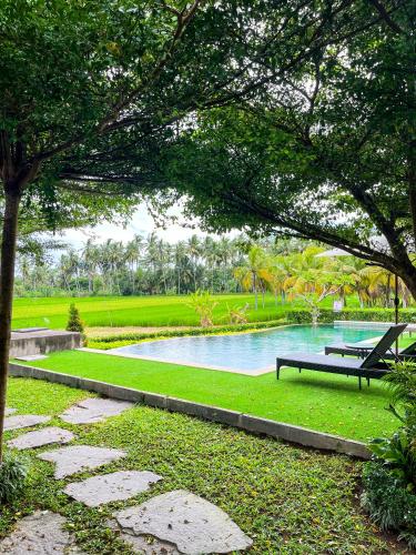 a park with a pond with a bench and a tree at Adil Villa & Resort in Ubud