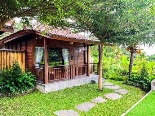 a small wooden house with a tree in the yard at Adil Villa & Resort in Ubud