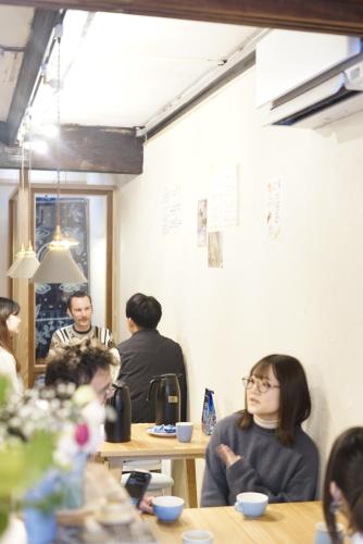 a group of people sitting at tables in a coffee shop at yohaku in Matsue