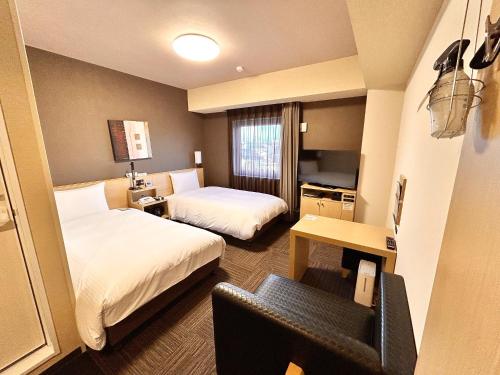 a hotel room with two beds and a chair at Hotel Route-Inn Anan in Anan