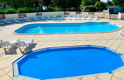 a large blue swimming pool with chairs and tables at Luxus Mobile Home beim Europa-Park, voll klimatisiert mit Wi-Fi! in Boofzheim