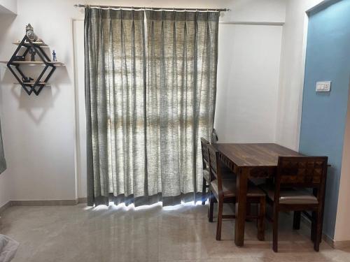 a dining room with a table and a curtain at Anahat Host all Back Packer 2BHK 2 Bed AC in Nashik
