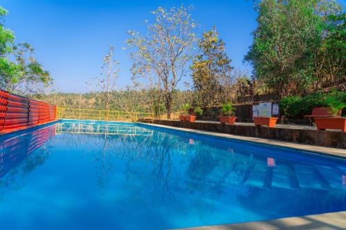 a swimming pool with blue water and trees in the background at Wild Camp- The Nature Resort in Khodāla