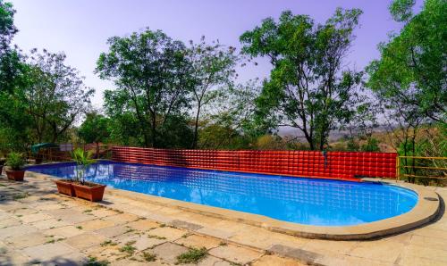 a swimming pool in front of a red brick wall at Wild Camp- The Nature Resort in Khodāla