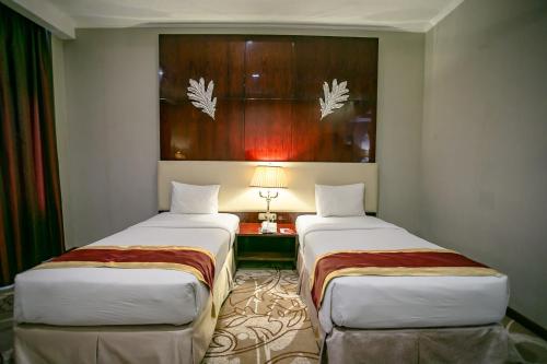 a hotel room with two beds and a lamp at Sutanraja Hotel & Convention Centre in Soreang