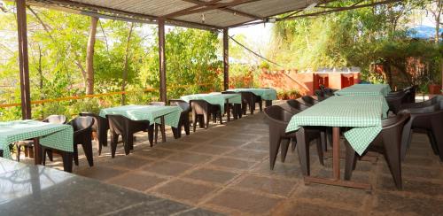 a row of green tables and chairs on a patio at Wild Camp- The Nature Resort in Khodāla