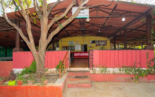 a building with a red fence and a tree at Wild Camp- The Nature Resort in Khodāla