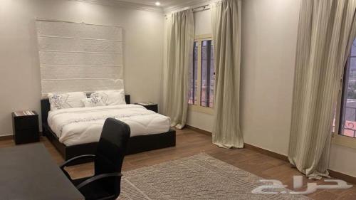 a bedroom with a bed and a chair and a window at شاليه وفيلا اطلالة الكر in Makkah