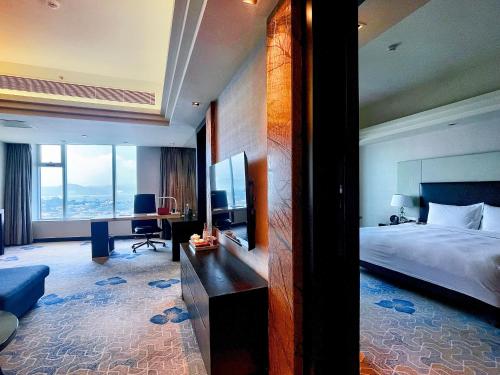 a hotel room with a large bed and a desk at Swiss Grand Xiamen-Harbour View in Xiamen