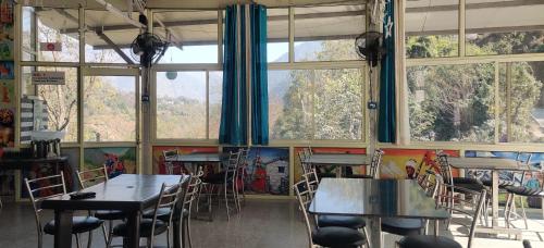a dining room with tables and chairs and windows at KC Hotel & Restaurant in Rudraprayāg