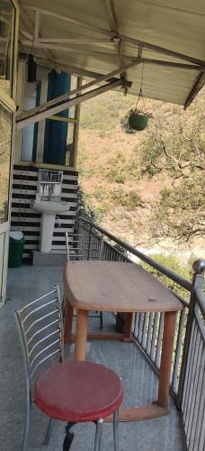 a wooden table and a chair on a porch at KC Hotel & Restaurant in Rudraprayāg