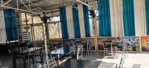 a dining room with tables and chairs and windows at KC Hotel & Restaurant in Rudraprayāg