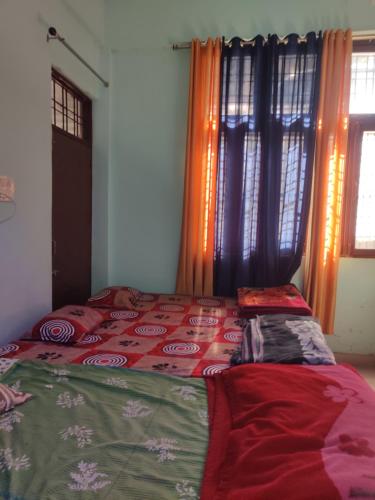 a bedroom with a bed with a red and green comforter at KC Hotel & Restaurant in Rudraprayāg